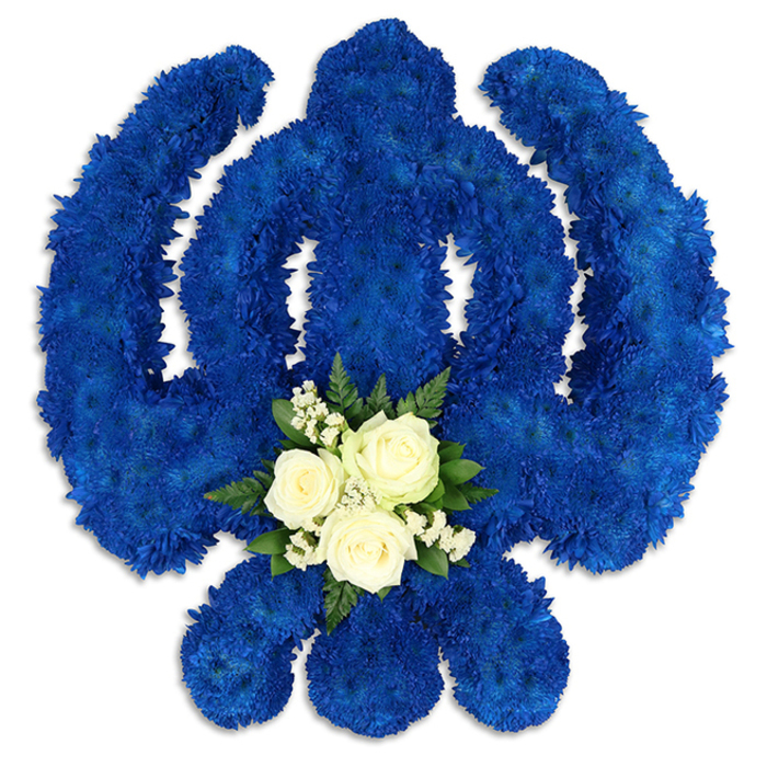 This image shows an elaborate Sikh Khanda funeral tribute, carefully arranged from fresh flowers and displayed against a pristine white background so every detail stands out. The entire symbol - the central double-edged sword, the surrounding circular chakkar, and the two curved kirpans that embrace it - is sculpted from countless royal blue chrysanthemums or similar cushion-type blooms. Each flower head is set close to the next, creating a seamless, velvety surface that gives the impression of a single, sculpted form rather than individual stems. The royal blue colouring is deep and noble, evoking dignity, spiritual strength, and a calm that feels fitting for a final farewell. Subtle variations in petal shape and shadow add texture, suggesting the gentle touch of a florist's hand placing each stem with patience and respect. At the lower centre of the design, where the eye naturally rests, a contrasting cluster of white and green flowers introduces softness and light. Three white roses sit at the heart of this cluster, their blossoms opening in perfect spirals, framed by clouds of tiny white filler flowers that resemble gypsophila. Around them, rich green leaves and perhaps a few fern tips peek out, grounding the arrangement and echoing the greenery you might notice in Queensbury's gardens and parks. The lighting is soft and even, casting faint shadows that lift the Khanda off the background, giving it a slightly three-dimensional, almost sculptural presence. Created with care by a local florist who understands Sikh traditions in and around Queensbury, this tribute feels ideal for a memorial, funeral, or anniversary of passing, expressing respect, remembrance, and unshakable devotion.