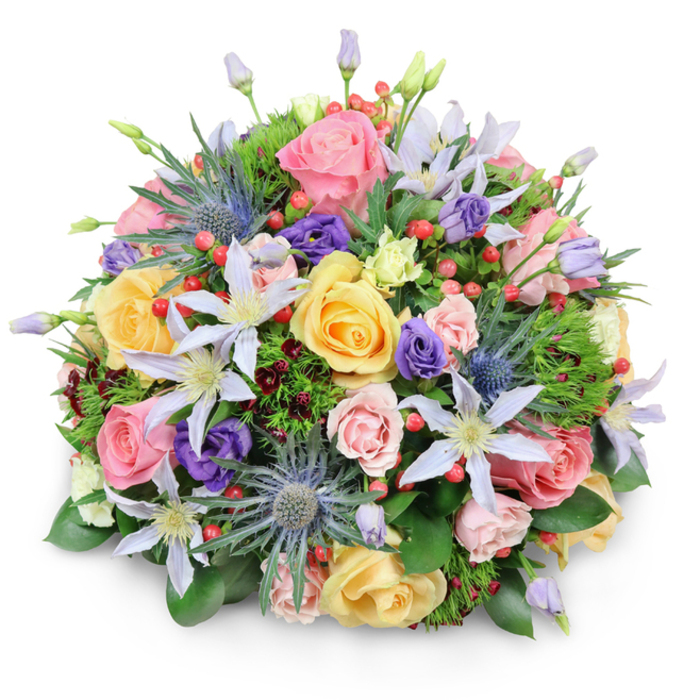 Set against a spotless white background, this meticulously arranged bouquet forms a near-perfect dome, like a little garden captured at its peak and brought indoors. The composition is densely layered, with each flower carefully placed so that colours blend yet remain distinct, echoing the quiet, residential charm of Queensbury's tree-lined streets. At the forefront are sumptuous garden roses in shades of soft pink, creamy peach, and mellow yellow. Some are fully open, revealing swirling hearts of tightly packed petals, while others remain in half-open buds that feel tender and new. Threading sinuously between them are star-shaped clematis flowers, their petals in tones of pale lavender and white, with central tufts of yellow that seem to glow against the cooler hues. Adding textural drama, several stems of blue Eryngium, or sea holly, project outward with thistle-like heads in metallic blue-grey, each surrounded by spiky bracts that lend a sculptural, slightly edgy quality. Deep purple lisianthus blooms, both budding and open, nestle closer to the roses, softening the transitions between pastel and jewel tones. Dotted throughout are clusters of small, bright red Hypericum berries, each berry smooth and rounded, creating a rhythmic pattern of colour that leads the eye through the bouquet. The flowers rest in a cradle of varied greenery, with glossy, substantial leaves supporting finer, feathery foliage and touches of almost burgundy-toned leaves that deepen the overall palette. The lighting is even and flattering, suggesting the careful presentation a Queensbury florist might use when photographing a favourite design for local customers browsing from home. The bouquet feels suitable for celebrations, thoughtful thank-yous, or simply brightening a living room near Queensbury Circle with an elegant, garden-inspired statement.