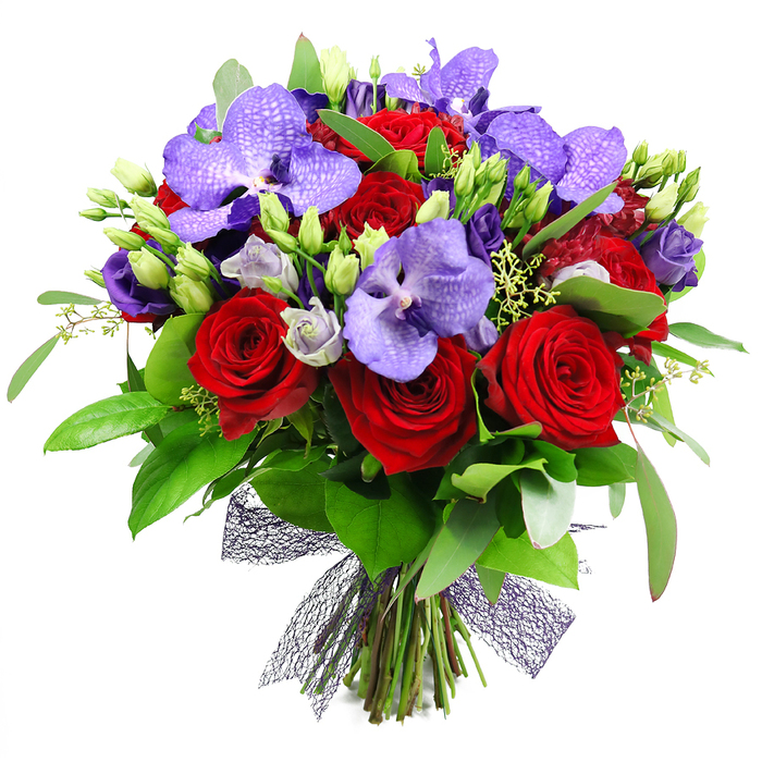 An opulent hand tied bouquet rises against a white backdrop in Queensbury, a refined blend of red and purple that speaks of passion and elegance. The fully opened red roses stand proud, their velvety layers catching the light, while purple Vanda orchids spread their broad, flat petals with a speckled finish that signals luxury. Between and around them, clusters of lisianthus in soft lilac soften the contrast and add delicate movement. The arrangement is framed by lush green foliage, from glossy broad leaves to slender sprigs that give volume and depth, with fresh green buds tucked in to invite the eye onward. The stems are gathered at the base and finished with a dark plum mesh ribbon that forms a textured bow, contemporary yet timeless.
This bouquet feels designed for celebrations, whether a milestone anniversary, a festive dinner party, or a grand thank you. Its colour story-rich reds, regal purples, and verdant greens-recalls the twilight hours over Queensbury's leafy streets and the warmth of a home prepared for guests. Freshness is assured by careful sourcing and daily delivery, with same-day service available across Queensbury and nearby districts, making this gift ready to delight a recipient from the High Street to nearby Edgware Road.