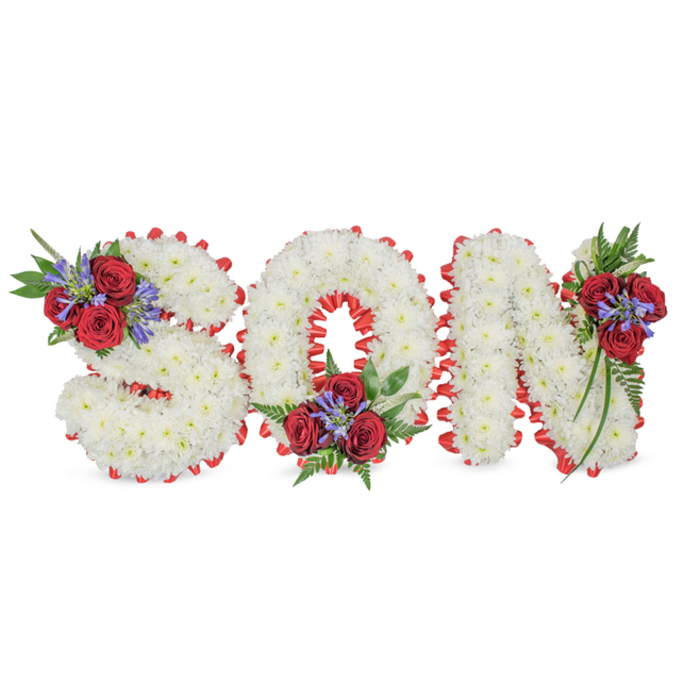 This poignant memorial design presents the word SON in bold, sculptural letters, each letter densely covered in pristine white spray chrysanthemums that create a cloud-soft, uniform surface. A striking scarlet satin border has been pleated into a scalloped edge around each character, the red tracing the contours and giving crisp definition to the S, O and N against a minimalist white setting. Tasteful clusters of deep red roses crown the top-left curve of the S, nestle into the lower curve of the O, and trail along the upright of the N, each grouping punctuated by spikes of blue-purple flowers reminiscent of Liatris or delphiniums and anchored by deep green, fern-like foliage and slender trailing leaves. The contrast between the cool white chrysanthemums, the rich crimson roses and the purple-blue accents produces a restrained but powerful palette that reads both classical and deeply personal. Soft daylight highlights the chrysanthemums' tiny petals and the satin's sheen while the aroma of rose and fresh foliage lingers gently. Intended as a bespoke condolence piece for a funeral service, wake or grave-side tribute, the arrangement balances formality with tenderness - a visual language of purity, enduring love and respectful farewell. Made with the sensibilities of a Queensbury neighbourhood florist familiar with families from Kingsbury and the wider NW London community, this piece is carefully finished so it can be displayed prominently during remembrance services.