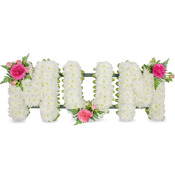 Set against a crisp white background, this touching floral tribute spells the word MUM in large, carefully shaped capital letters, crafted with the quiet precision of a florist who understands the tenderness of farewell. Each letter is completely filled with hundreds of small, snow-white chrysanthemum blooms, placed so closely together that they create a smooth, cushioned surface, like a soft blanket of petals. The uniformity of the chrysanthemums symbolises purity, remembrance, and the gentle constancy of a mother's love. Along the base of the letters, a dark green frame or band can be just seen, linking the shapes together and offering practical support, reminiscent of the steady reliability of family life in Queensbury's residential streets. The stillness of the white is gently broken by three artfully placed clusters of pink and green. At the upper left of the first M, a prominent fuchsia-pink garden rose, possibly an open peony-style bloom, is nestled among smaller, paler pink spray roses, with graceful fern fronds that fan out to add airy movement and a fresh woodland feeling. A similar grouping rests in the lower curve of the central U, tucking softness and colour into the heart of the design, and another matching cluster crowns the top right of the final M. The combination of pure white chrysanthemums with vivid pink roses speaks of both grief and gratitude, offering a dignified, personal way to honour a mother's memory at a funeral service, memorial gathering, or graveside visit anywhere across Queensbury and the surrounding area.