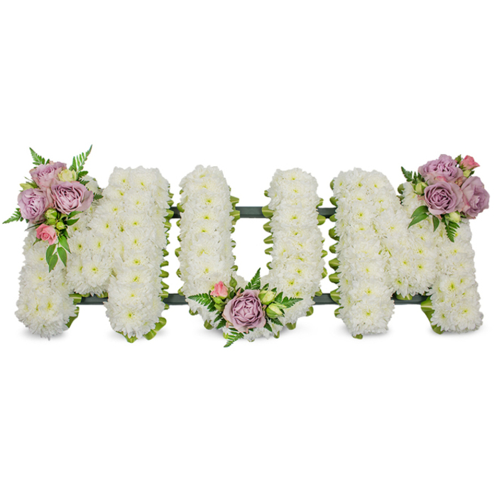 A beautifully staged memorial piece spells out MUM in large, crisp capital letters, each letter meticulously covered with hundreds of small, fresh white chrysanthemums to create a uniformly plush surface that reads as soft and reverent. Set against a pure white background, the arrangement is punctuated by three carefully placed accent clusters of muted lavender roses and gentle pink rosebuds: one graces the upper left arm of the first M, another sits in the central sweep of the U, and a third rests on the upper right arm of the final M. Interspersed with bright green foliage and fern-like fronds, the clusters add depth, a touch of colour, and a natural rhythm across the composition. A dark green, ribbon-wrapped or mossed structural frame is visible at the base, anchoring the letters and ensuring the tribute retains its shape when placed on a chapel stand or at a graveside. The scent is quietly floral - soft rose notes over the cleaner, subtler chrysanthemum aroma - and the overall tone is one of peaceful remembrance and tender respect. As local florists serving Queensbury, Kingsbury and the surrounding streets toward Wembley, Flower Delivery Queensbury designs this classic sympathy tribute to convey heartfelt condolence. It is a tasteful, traditional choice for a mother's funeral, wake, or memorial service, created to sit with dignity among floral tributes and to help hold loved ones' memories with grace.
