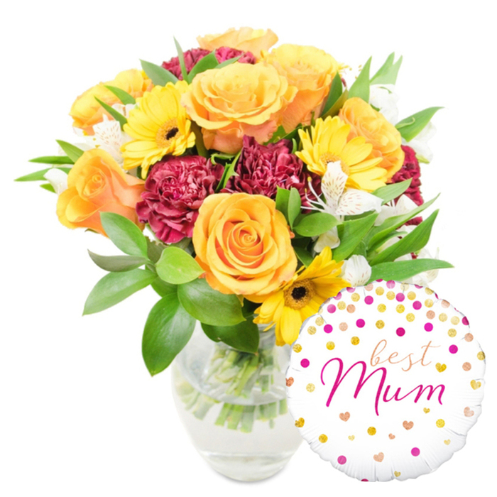 A bright, affectionate floral gift arranged with calm attention and photographed on a pure white field, this bouquet pairs classic bloom forms with a playful, personal balloon. Prominent peachy-orange roses dominate the silhouette, each bloom opening with layered, velvety petals that suggest warmth and tenderness. Cheerful yellow gerbera daisies appear like little beacons among the roses, their radiating petals and deep dark centres bringing an immediate sense of sunshine. Contrasting with the lighter tones are deep red-burgundy carnations, their many ruffled petals creating plush texture and visual weight. Interspersed throughout are delicate white alstroemeria - narrow-petalled and subtly speckled - which introduce a refined, airy counterpoint. The composition is rounded out by abundant green foliage, from glossy, broad leaves to slim, textural sprigs that give the bouquet body and a freshly cut garden presence. The arrangement is placed in a clear glass vase so the stems and clean water are visible, inviting the viewer to sense the recent care taken in trimming and conditioning. At the lower right, a round white Mylar balloon overlaps the vase, adorned with scattered gold and fuchsia dots and tiny hearts; the central handwritten-style message reads best Mum in elegant hot-pink script. The mood is celebratory yet intimate - perfect for a Mother's Day table centrepiece or a doorstep surprise for a Queenbury resident, whether delivered to a flat near the tube or a house by the local high street.
