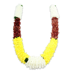 A richly coloured, U-shaped ceremonial garland poised against a clean white backdrop, the faint shadow beneath hinting at careful studio lighting that highlights texture and form. The garland starts at each top end with a compact, cylindrical section of creamy white, small-petalled blooms that read like miniature chrysanthemums or jasmine-soft, compact and auspicious in appearance. That white quickly transitions into a deep maroon or rust-red band of tightly arranged synthetic petals, providing a warm, grounding contrast. The main length of each arm flows into long, sunny yellow sections, densely packed to imitate marigolds and forming the broad, plush curve of the U. Where the two yellow halves meet at the bottom, a generous cluster of bright white, chrysanthemum-like flowers creates a striking central focal point. Small, dark green leaf accents are tucked between colour changes, especially at the junctions of yellow and white, giving the piece a considered, natural rhythm.

As a Queensbury florist I recognise the practical beauty of this artificial mala: thousands of fabric petals are carefully arranged to capture the look of fresh flowers while offering durability for temple offerings, weddings, or community festivals. The colours-white for purity, yellow for prosperity, maroon for devotion-carry cultural meaning and are often chosen for puja, garlanding guests, or altar decoration. Flower Delivery Queensbury often prepares similar garlands in our workshop near Queensbury Station and The Broadway for local ceremonies and events; the photograph conveys both the artisan's hand and the enduring symbolism of the piece.