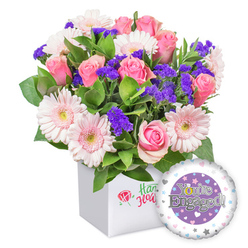 From Flower Delivery Queensbury, this vibrant engagement bouquet arrives in a crisp white square box, a sleek presentation that suits modern living rooms across Queensbury, Kingsbury, and Burnt Oak. The arrangement centers on several soft pink roses, their petals unfurling in gentle spirals, paired with cheerful pastel pink gerbera daisies that boast white-edged petals and pale yellow centers for a sunny touch. Interspersed are clusters of deep purple statice, adding drama and texture without stealing the show from the roses. Lush green foliage provides a natural frame, giving the bouquet a garden-fresh feel. A round foil balloon rests in the lower right, its silver lettering declaring "You're Engaged!" on a central purple disk, bordered by a white ring studded with tiny hearts in pink, blue, and grey, plus delicate silver stars. This ensemble reads as confident, affectionate congratulations for an engaged couple, ideal for brightening a kitchen table or office desk. We offer reliable same-day delivery across NW9, including Queensbury, Kingsbury, and Burnt Oak, so the moment can be shared quickly with the people you care about. The box carries a discreet emblem rather than branding, keeping the focus on blooms and the message of joy. It's a gift that radiates warmth, love, and bright possibilities for the couple's future together.