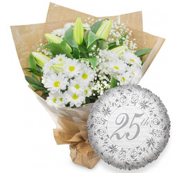 This image shows a graceful Silver Anniversary gift set that feels perfectly suited to a quiet celebration in Queensbury, perhaps after a leisurely stroll near the local green spaces. The main focus is a lush hand-tied bouquet of white flowers positioned on the left against a bright, uncluttered white background. Dozens of white chrysanthemums, daisy-like in form with cheerful yellow centres, create a full, rounded heart to the arrangement. Rising through them are several tall white lily buds, their petals still folded and edged with soft green, suggesting new chapters yet to open in a long marriage. Between these, tiny clusters of white baby's breath add a misty texture, as if a light haze has settled over the bouquet, while deep green leaves frame the blooms and anchor them visually. The stems are enclosed in smooth cellophane for protection, then wrapped in natural brown kraft paper folded into gentle angles, giving a handcrafted look reminiscent of flowers bought from a favourite Queensbury market stall. At the base, the paper is gathered and tied neatly, hinting at the care taken by an experienced local florist. To the right, a gleaming round silver foil balloon balances the composition. Its metallic surface reflects subtle highlights and is printed with ornate swirls and floral scrollwork in muted silver tones. At its centre, the large, flowing script reads "25th," surrounded by softly repeating "Happy Anniversary" phrases that fade into the background. Together, the calm white blooms and sophisticated silver balloon create a quiet yet unmistakable message of milestone celebration and long-lasting devotion.