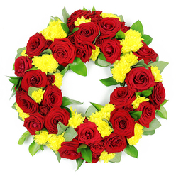 A beautifully balanced circular funeral wreath, photographed against a clean white background, is composed of nothing but rich reds, bright yellows, and layers of fresh green foliage, like something lovingly prepared in a Queensbury flower shop before a memorial. Deep red roses dominate the design, each one fully open yet still firm, with petals that curl gracefully outward in smooth, velvety layers. Their colour ranges from classic, true red at the outer petals to slightly shaded crimson and wine tones toward the centre, adding depth and a sense of quiet intensity. Threaded between these roses are generous clusters of yellow chrysanthemums, their many thin petals forming round, soft domes that catch the light and lend the arrangement a gentle glow. The contrast between the roses' satin-like surfaces and the chrysanthemums' feathery texture makes the wreath feel almost touchable, as if you might brush your fingers over the blooms and feel the difference. Around and beneath the flowers, abundant greenery fills the circular frame: sturdy, deep-green leaves with a subtle shine sit beside cooler, grey-green sprigs that could be eucalyptus, suggesting a soft herbal scent. The flowers and foliage are bound tightly together in a perfect ring, leaving a clear open centre that emphasises the symbolic notion of eternity and remembrance. The white backdrop and strong, even lighting make every shade and texture stand out, highlighting the craftsmanship and care behind the piece. This wreath would sit with quiet grace at a funeral or graveside gathering in Queensbury, perhaps after a final farewell at a local church off Kingsbury Road, expressing both sorrow and enduring love.