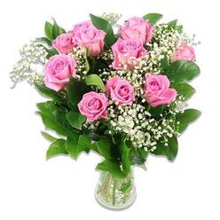 A delicate yet abundant bouquet of pink roses and baby's breath is shown in clear detail, standing proudly in a transparent glass vase against a pure white background, like a freshly delivered gift to new parents in Queensbury. At the centre, approximately ten to twelve pink roses create a rounded, luxurious cluster, each bloom shaped by layers of satiny petals that curve outward in gentle spirals. The pink tones range from a tender, baby-blush hue at the outer petals to a richer rosy shade tucked into the depths of the flower, adding a feeling of warmth and emotion. Interwoven among the roses are airy sprays of white Gypsophila, or baby's breath, their tiny blossoms forming a soft halo around the larger heads, which gives the arrangement a dreamy, almost cloud-like quality that feels perfect for celebrating a newborn. Surrounding the blooms, deep green foliage frames the design, with slightly serrated rose leaves catching the light and offering a cool, fresh contrast to the warm pink petals. The stems are neatly trimmed and visible through the glass vase, resting in a shallow pool of clear water that reinforces the sense of freshness and care. The even, bright lighting makes the colours vivid while still gentle on the eye, evoking the calm, joyful atmosphere of a nursery prepared for a baby's arrival near Queensbury Park. This classic, romantic arrangement feels thoughtfully composed, ideal for baby girl bouquets, welcome-home-from-hospital flowers, or simply to brighten a family home near Kingsbury Circle with a message of love, new beginnings, and quiet celebration.
