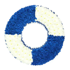 Set against a bright white backdrop, this lifebuoy-shaped funeral wreath has been created with the kind of care and precision you might expect from a small, experienced florist serving families around Queensbury and the surrounding streets. The design is clean and unmistakably nautical: a perfect ring of flowers divided into four equal blocks of colour, alternating between dark royal blue and clear, snowy white. Each segment is densely covered in small chrysanthemum-type blooms, their petals overlapping in tight clusters so that the ring appears lush and solid, almost like a soft cushion of colour. The blue quadrants on the top left and bottom right feel deep and contemplative, their cool tones echoing the calm of open water, while the white quadrants on the top right and bottom left add lightness and a sense of peace. If you could run your hand over the surface, you would feel a fine, slightly uneven texture where each bloom rises just a touch above its neighbour. Framing the inner circle, a neat dark blue ribbon has been gathered into tiny pleats, echoing the colour of the sea and tracing the central opening that makes the piece so clearly resemble a classic life ring. This tribute is clearly intended as a sympathy or funeral arrangement, ideal for remembering someone who spent years working on the water, volunteering with rescue services, or simply being a "lifesaver" in the lives of those in Queensbury who loved them. The overall effect is one of dignity, gratitude, and unwavering support in a time of loss.