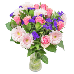 As I piece together this luminous bouquet in our workshop near Queensbury's bustling markets, I'm captivated by the interplay of soft blush gerberas and noble pink roses. The arrangement glows with the gentlest washes of coral and rose, the colours drifting together like watercolours beneath the soft spring morning light that filters across Church Lane. Dotted throughout, the deep violet of statice flowers offers a charming contrast, each spike catching the eye and invigorating the mood. The bouquet's greenery is fresh and dewy, cool to the touch-evoking the natural breeze of nearby Canons Park-while the blooms themselves float gracefully above, their petals layered with depth and gentle movement. All are gathered in an understated glass vase that frames the composition with subtle elegance. The overall effect is uplifting and optimistic, as if bringing Queensbury's first blossoms of the season directly into your living room. This arrangement is versatile, equally stunning as a cheerful get-well wish or a bright addition to a modern home on Beverley Drive. Every detail, from foliage to flower, is chosen for its freshness and meaning, reflecting the dedication of local florists and the joy present in every subtle shade.