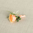 In the soft, diffuse light of an early day this peach rose boutonniere radiates a calm, careful beauty: its petals layered from a deeper golden-apricot centre to a delicate peach rim, each fold catching light and shadow with subtle depth. Tiny clusters of baby's breath hover nearby like starlight, lending a feathery, innocent punctuation to the composition, while narrow loops of deep green foliage create a tidy, grounding frame that lifts the rose and gives the piece a fresh, lively silhouette. The stem is bound in a matching peach satin, wrapped smoothly and finished with a small, neat bow that hints at the maker's steady hand and attention to proportion. There is a tactile contrast between the silky ribbon, the velvet-petal softness, and the slight crispness of the leaves that invites touch - not intrusive, but reassuring, like a practiced flourish. As a local florist I often prepare boutonnières like this for couples marrying near Queensbury tube and for receptions in Canons Park or the nearby community halls; the piece complements both formal suits and relaxed spring celebrations. The photograph is lit to emphasise texture: the neutral linen backdrop softens shadows and allows the warm peach tones to breathe, while the composition keeps the eye moving from the bloom's luminous centre out to the airy gypsophila and the finished stem. This boutonniere feels like a small promise - quietly joyful, elegantly made, and ready to be pinned by a steady hand on a wedding day in Queensbury or slipped into a keepsake box afterwards.