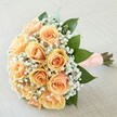 Perfectly poised on a light, textured cloth, this hand-tied bouquet exudes a quiet, gentle elegance-its beauty at home among the cherished ceremonies of Queensbury. Tightly clustered roses, their peach and apricot petals unfurling in soft spirals, radiate a warm glow that feels as timeless as it does fresh, recalling the first blooms of spring in Chandos Recreation Ground. Wisps of white gypsophila encircle the roses, their fine, airy blossoms amplifying a sense of lightness, much like delicate lace adorning a bride's dress. Glossy dark green leaves peek around the edges, providing balance and echoing the abundance of foliage seen throughout Queensbury's peaceful avenues. The stems are neatly gathered and encompassed by a peach ribbon, silky to the touch and elegantly dotted with pearls arranged in a subtle, geometric pattern that hints at classic wedding tradition. This bouquet seems to capture the sweet anticipation and soft hope of a joyous day, releasing a gentle fragrance that brings to mind garden walks on quiet NW9 afternoons. Whether chosen for a wedding, anniversary, or a moment meant to linger in memory, it offers a soothing blend of artistry, freshness, and subtle romance-an evocative signature for the heart of Queensbury.