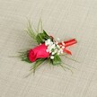 A single, exquisitely crafted boutonnière lies diagonally across a softly textured, light beige fabric, the weave reminiscent of natural linen often seen in elegant Queensbury venues. At its heart rests a tightly furled rosebud in a rich fuchsia-deep magenta tone, the petals smooth and velvety, cupping into a perfect spiral of colour that seems ready to unfurl at the first notes of a wedding march. Nestled closely around the central bloom are airy tufts of tiny white baby's breath, each minuscule flower creating a cloud-like halo that softens the rose's bold intensity and adds a sense of lightness and movement. Behind and around the blooms, slender sprigs of fresh, bright green foliage splay out in gentle arcs, some feathery and grass-like, others slightly broader, giving the arrangement a natural, garden-picked charm that feels right at home for a ceremony near Queensbury Park or a celebration along the surrounding residential streets. The stems are gathered into a neat bundle and wrapped with a thin, glossy red satin ribbon, wound tightly and smoothly so that no loose ends show, adding a refined, polished finish that complements the rose's pink tones. The lighting in the image is bright and even, highlighting every vein in the petals and each bead-like blossom of gypsophila, conveying freshness, care, and the calm anticipation of a special day. This boutonnière, perfect for a groom, groomsman, or prom guest, evokes romance and tradition while reflecting the quiet sophistication of a thoughtfully arranged floral accessory chosen for a formal event in Queensbury.