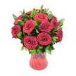 A lush, romantic bouquet of around a dozen deep red roses is gathered in a rounded, almost dome-like shape and set in a translucent ruby glass vase, all shown against a clean white studio background. Each rose head is fully open yet still fresh, with velvety petals spiralling inward in tight, intricate layers that create a plush, almost satin texture. The red is intense and uniform, closer to rich crimson than bright scarlet, giving the arrangement a sense of luxury and passion that would feel perfectly at home in a candlelit Queensbury townhouse or a cosy flat off the main high street. Between the blooms, generous sprigs of dark green foliage, likely ruscus, fan out with glossy, lance-shaped leaves that catch the light and frame the roses, adding fullness and a natural rhythm to the design. The vase itself is a deep red glass with a flared rim and gently curving sides that taper towards the base, its subtly ribbed or undulating finish catching reflections like ripples. Light filters cleanly across the scene, with no harsh shadows, making the reds and greens stand out sharply from the white background and drawing the eye directly to the flowers. You can imagine the soft, sweet fragrance of fresh roses filling a living room near Queensbury Park, turning the bouquet into a quiet but unmistakable declaration of love. This image captures a timeless gesture-perfect for anniversaries, Valentine's surprises, or any heartfelt delivery across Queensbury where red roses are meant to speak for you.