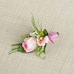 Evoking refined romance and local artistry, this beautifully crafted boutonniere is set against a softly woven, oatmeal-hued linen, with every detail catching the gentle daylight found on a Queensbury morning. The arrangement is anchored by a central rosebud of pastel pink, its petals tightly rosetted in a graceful spiral suggestive of pure freshness and quiet emotion. Close by, a peach-hued Alstroemeria opens, its subtle yellow throat patterned with inky dots providing a painterly touch. Interspersed throughout, stars of white baby's breath add breezy softness, while little green cushion mums bring texture and zest, much like the neatly-kept borders of nearby Queensbury gardens. An array of foliage-wispy, upright blades and broader, darker leaves, some artistically folded-provides structure as well as a lush, spring-green frame to the flowers. The stems are wrapped in a glowing strip of fuchsia pink satin, tied in a small neat bow to finish the composition with a splash of joy. This boutonniere, expertly composed by a local florist, feels right for weddings at the heart of Queensbury or festive occasions along the community's welcoming avenues. Understated yet memorable, it's an accessory that would grace the lapel of a groom or guest, symbolizing elegance and the enduring beauty of thoughtfully gathered blooms.