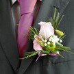 There's a quiet elegance in this carefully composed boutonniere, beautifully showcased as it rests against the smart lapel of a charcoal grey suit-an image evocative of celebrations along Queensbury's residential streets. Soft morning light falls gently on the ensemble, highlighting the vibrant fuchsia tie and the crisp collar of the shirt beneath. But it's the floral arrangement on the lapel that draws the eye: a pale pink rose, its petals softly opening as if whispering stories of romance and tender beginnings, nestles beside a subtly striped pink alstroemeria. Clusters of tiny white gypsophila, so reminiscent of early summer bouquets from Flower Delivery Queensbury, weave in between, their delicate fluffiness speaking of both tradition and the innocence of new unions. A button of bright green chrysanthemum peeks out for a burst of freshness, harmonised by feathery fern tendrils and arcing green blades that add both shape and movement. The base of the design is tidily finished with a lustrous lavender ribbon bow, its colour echoing the pink hues and adding a final touch of refinement. The image as a whole radiates the thoughtful artistry and emotional resonance that locals seek for weddings and special occasions in Queensbury-capturing a blend of style, care, and authentic celebration.