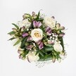 A luxuriously full bouquet is photographed from directly above against a spotless, bright white background, so every flower and leaf stands out with crystal clarity. At the heart of the design, several creamy white to soft ivory roses unfold in different stages of bloom, from tight, pale buds with a hint of buttery yellow at their centre to generously opened rosettes with many layered, spiralling petals. Threaded between the roses are elegant alstroemeria, or Peruvian lilies, in mauve, lavender and berry-pink tones, some still slender and closed, others unfurling to reveal petals stroked with soft green veining and speckles. Delicate sprays of tiny white gypsophila, or baby's breath, drift between the larger blooms like scattered clouds, adding a fine, misty texture that softens every edge. A collar of deep green foliage, broad and glossy, cradles the flowers and gives the arrangement a sense of structure and freshness, as if it has just been gathered from a well-tended garden on the edge of Queensbury Park. The lighting is clean and even, with no harsh shadows, which enhances the bouquet's serene, romantic mood and the subtle contrast between cool ivory and warmer pink-purple tones. This overhead image would feel at home on a local florist's workbench along Church Lane, capturing a bouquet ready to be hand-delivered for a birthday, an intimate Queensbury wedding, or a thoughtful thinking of you gesture. The overall impression is of quiet sophistication and gentle emotion, an arrangement that communicates care and sincerity without a single bloom feeling out of place.