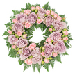 This image shows a full, circular funeral wreath photographed from above against a bright white background, allowing every flower and leaf to stand out with clarity. The wreath is abundant with roses, the largest blooms a sophisticated mix of dusty lavender, antique mauve, and soft grey-purple, each fully open and layered with countless velvety petals. They form the main structure of the design, their placement carefully spaced to create a harmonious, unbroken ring. Nestled between these are clusters of blush-pink spray roses, some still in bud, others half-open, giving the arrangement gentle variety and a tender, almost storytelling quality, as if marking different chapters of a life. The pastel colours blend in a soothing way, making this wreath especially fitting for a memorial or funeral service for a loved one from Queensbury or the surrounding streets near Kingsbury and Edgware. Beneath the flowers, a strong base of deep green fern fronds supports the design. The ferns' feathery, serrated leaves extend outward, overlapping and filling every gap, creating a rich green halo that frames the roses and emphasizes the circular form. Small hints of darker foliage and discreet buds between the blooms add subtle contrast and depth, ensuring the wreath feels lush and three-dimensional rather than flat. The overall lighting is soft and diffuse, capturing the natural textures of each petal and leaf without glare. The mood is serene and respectful, evoking condolence, remembrance, and peace. It feels like a loving tribute a local florist might prepare for a farewell gathering, offering comfort and beauty in a time of loss.
