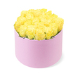 A chic pastel pink hatbox overflowing with yellow roses is displayed against a bright white background, creating a crisp, contemporary portrait of modern floristry. The cylindrical box stands upright and symmetrical, its soft, matte surface suggesting a velvety or suede-like material that feels indulgent to the touch, the sort of finishing detail you might associate with a high-end florist near Queensbury station. Its delicate blush tone acts as a quiet frame for the striking flowers above. The top of the hatbox is completely filled with roses - approximately two dozen fresh, carefully arranged blooms - forming a gently rounded crown of petals that spills just slightly over the edge. Each rose is at that perfect stage of opening where the petals are neither too tight nor fully unfurled, creating a sense of lush fullness while still retaining their elegant shape. The colour is a radiant, sunshine yellow, evoking feelings of cheerfulness, friendship, and new beginnings, with subtle gradations from creamy centres to more intense golden tips. Small touches of green foliage can be glimpsed between the blooms, adding a whisper of contrast and enhancing the natural look. Soft, even lighting brings out the richness of the colours without casting heavy shadows, so the arrangement appears fresh and inviting, as though just delivered to a doorstep in Queensbury for a birthday breakfast or an anniversary surprise. The overall impression is one of refined joy and thoughtful gifting, a versatile design suited to brightening offices, homes, or intimate celebrations, perfect for those moments when you want to send a discreet yet unmistakably uplifting message in flower form.